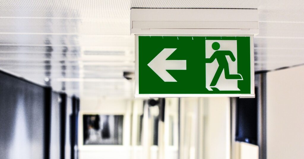 Illuminated emergency exit sign guiding evacuation in an office hallway